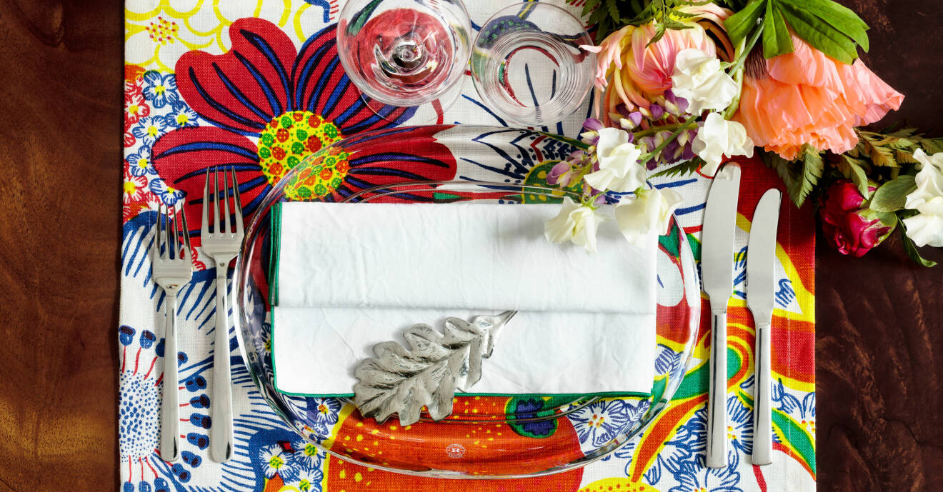 En bordsdukning med Josef Frank tyg, blommor och ett eklöv i silver.