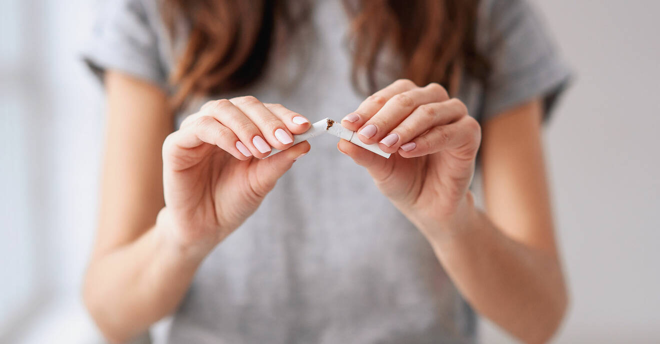 Kvinna bryter en cigarett för att visa att hon slutat röka.