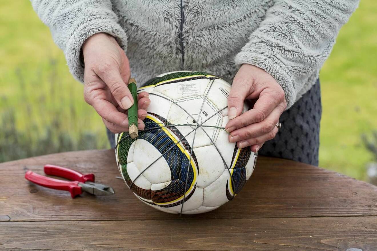 Kvinna visar upp ståltråd, avbitartång och fotboll som ska bli ett hemgjort spaljéklot 