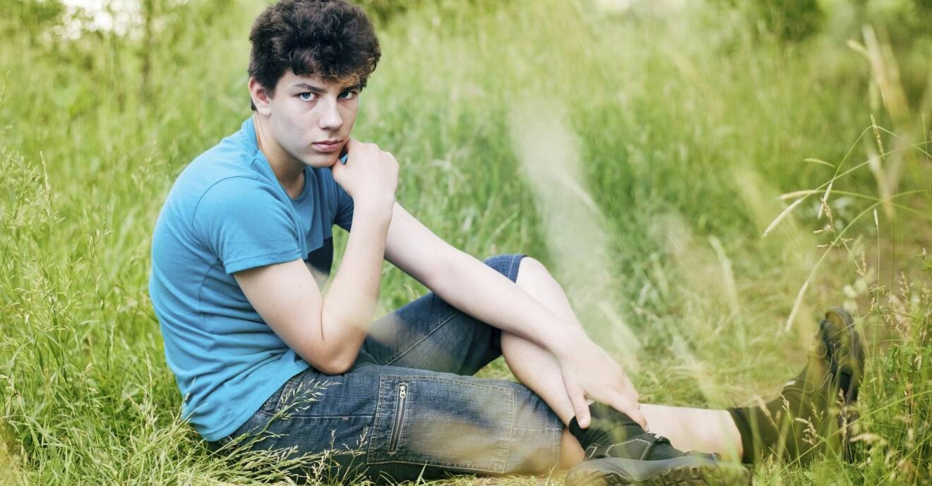Bekymrad ung kille sitter i gräset.