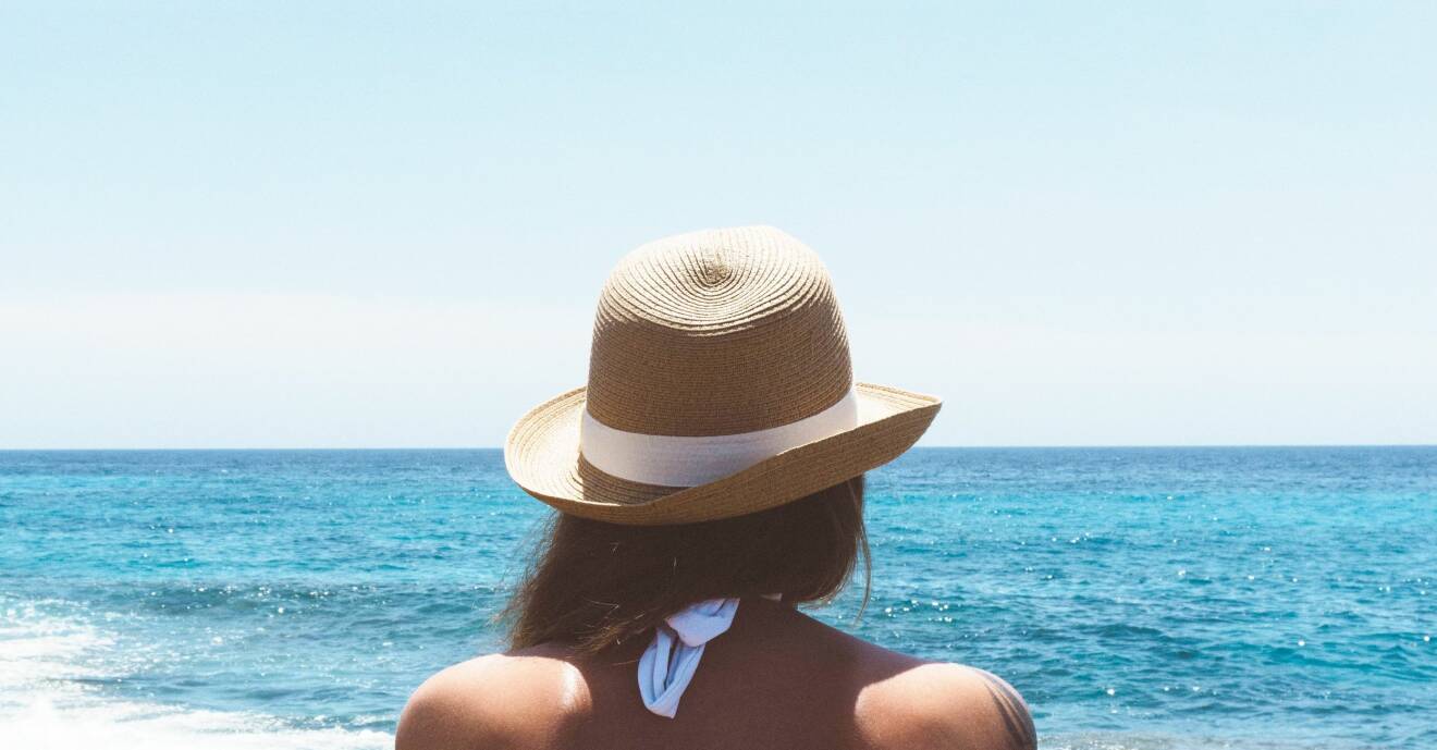 Kvinna med solhatt på stranden