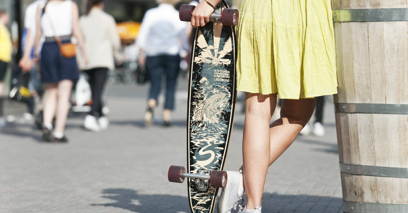 Kvinna med klänning och skateboard