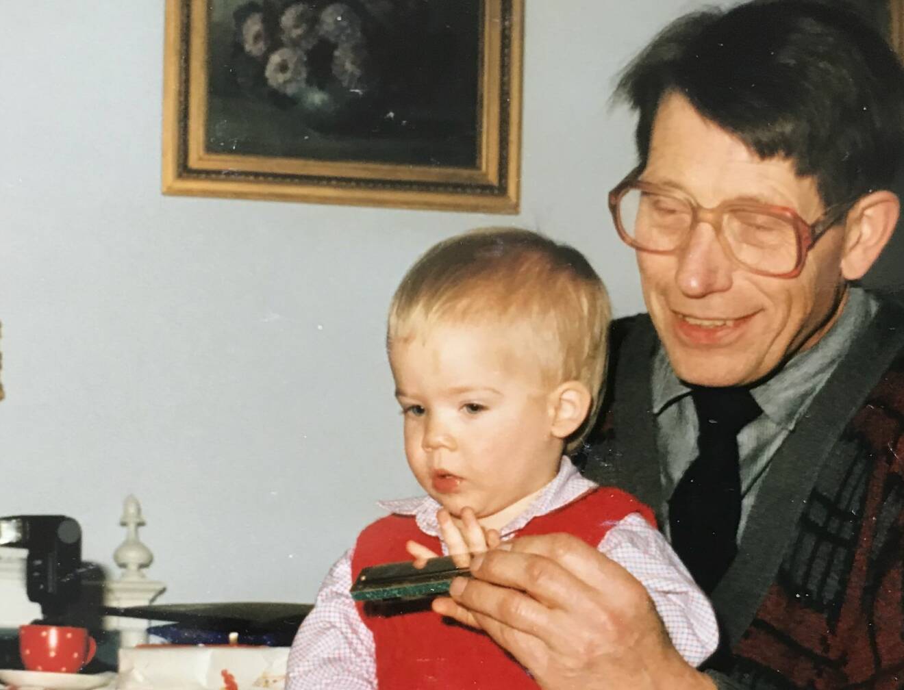 Nils med munspel i knät på sin morfar.