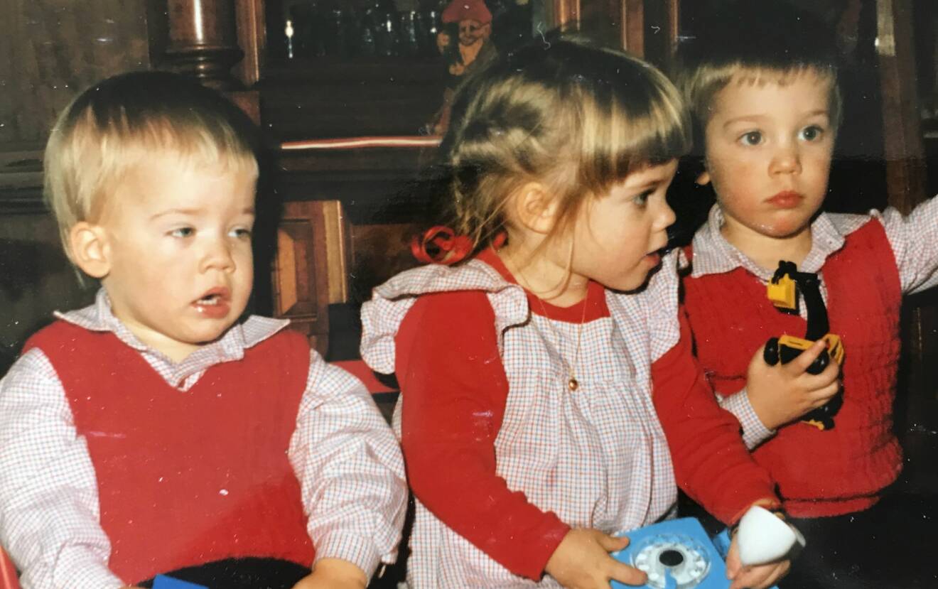 Nils och storasyskonen klädda i rött och vitrutigt på barndomsfoto.