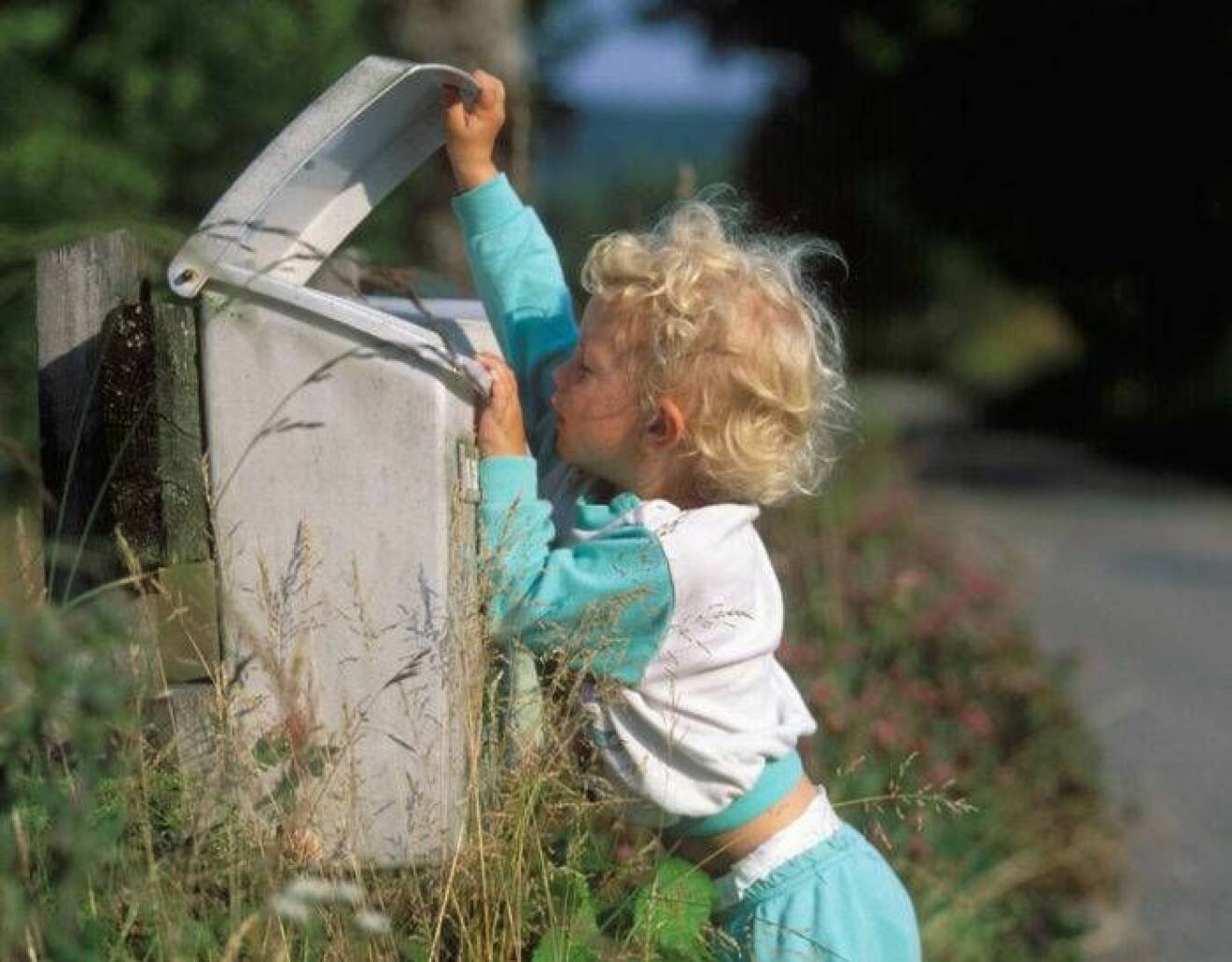 En pojke inspekterar brevlådan.