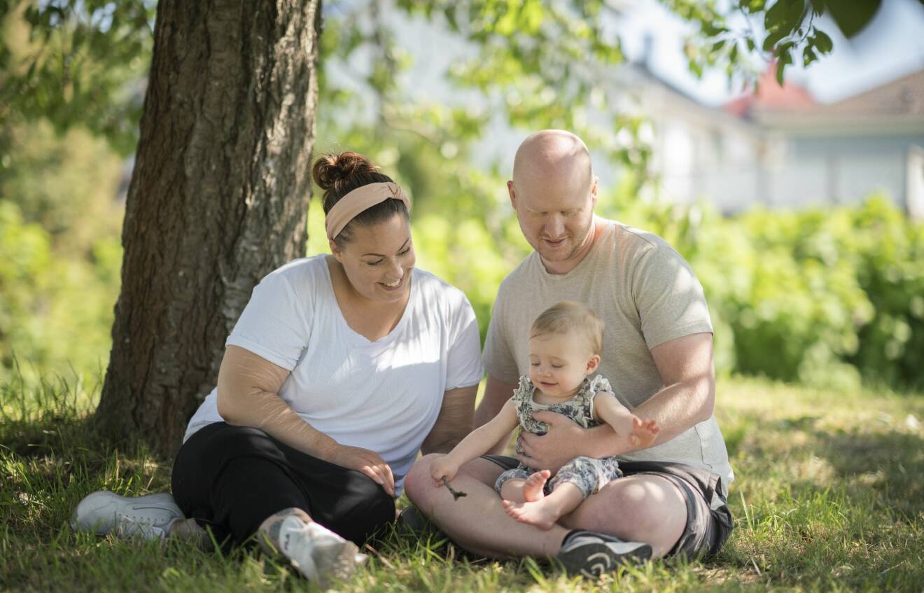 Pia Ejeklint och Jonas Skoog sitter på gräset tillsammans med dottern Lowa.