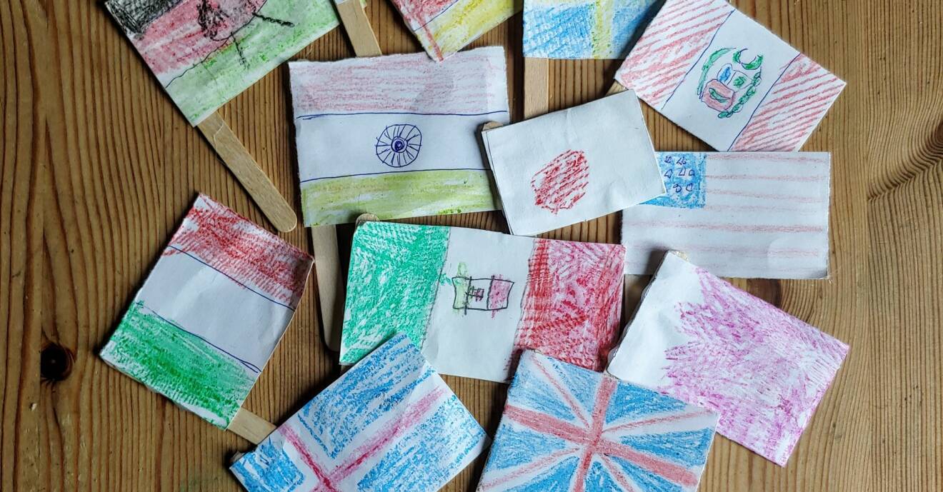 Olika länders flaggor ritade på små lappar fäst på glasspinnar.