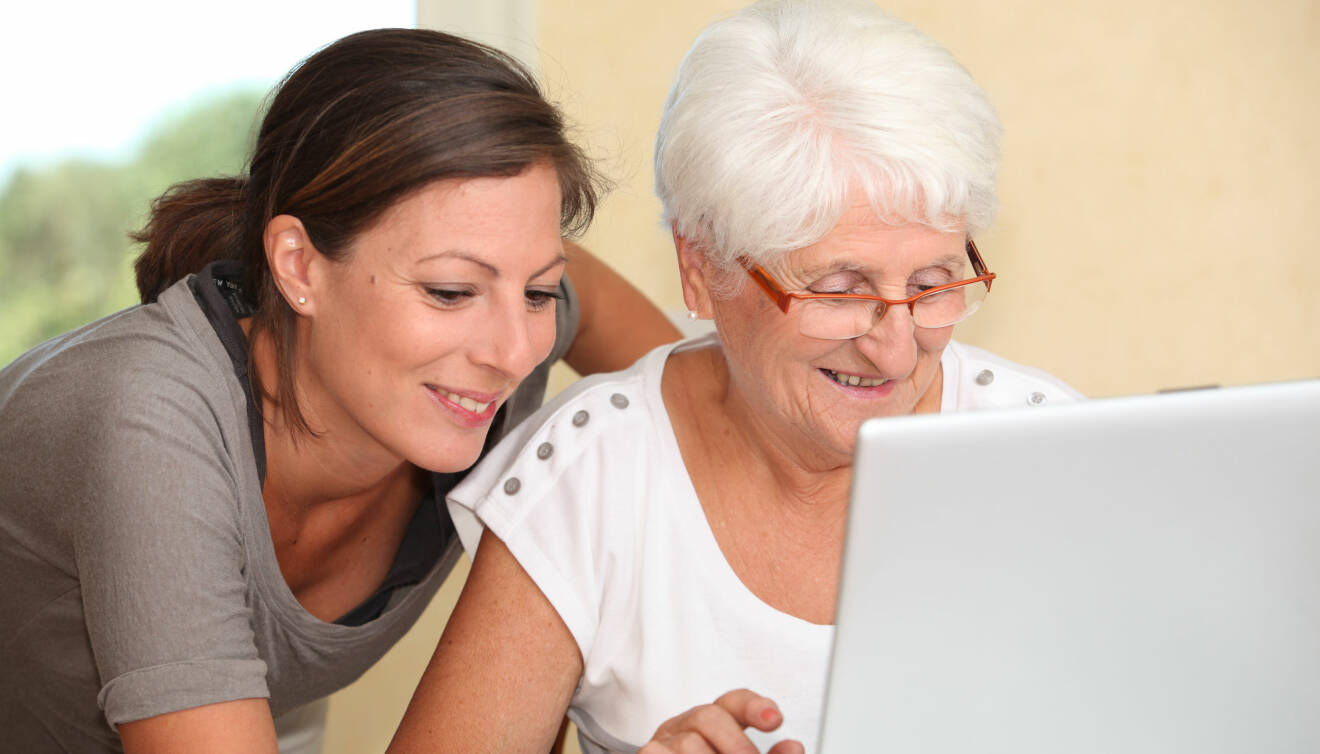 Kvinna hjälper äldre kvinna att handla på internet.
