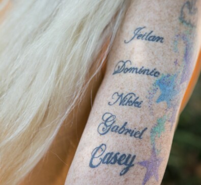 Anette har sina barnbarns namn tatuerade på ena armen: Jeilan, Dominic, Nikki, Gabriel och Casey. Namn tatuerade på överarm på kvinna.