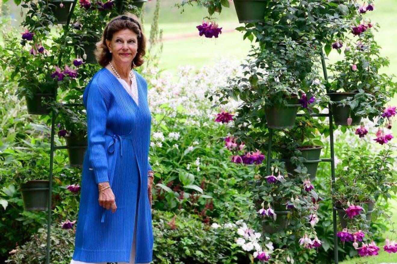 Porträtt av drottning Silvia i en blomstrande trädgård sommaren 2020.