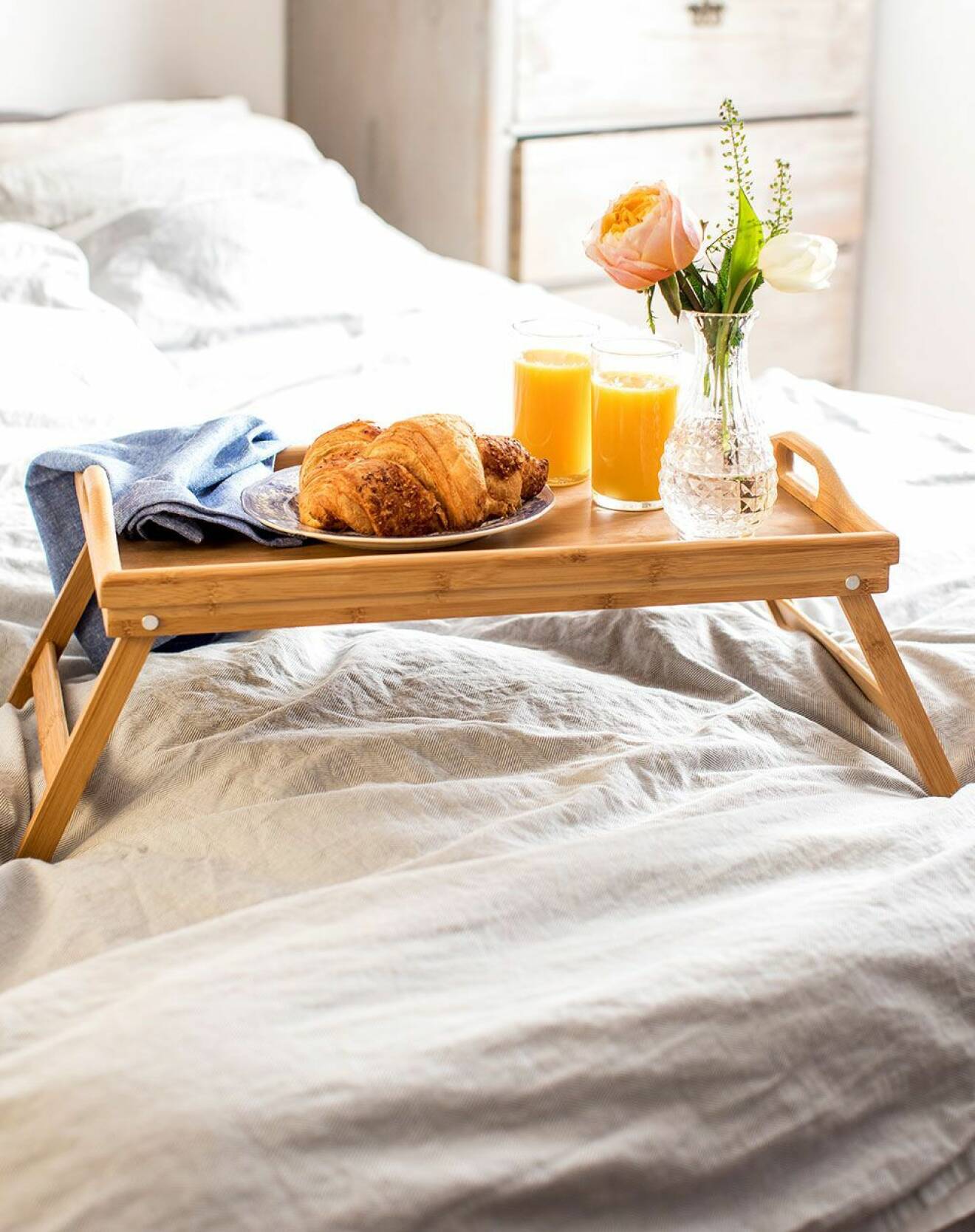 Frukostbricka på ben som står i en säng.