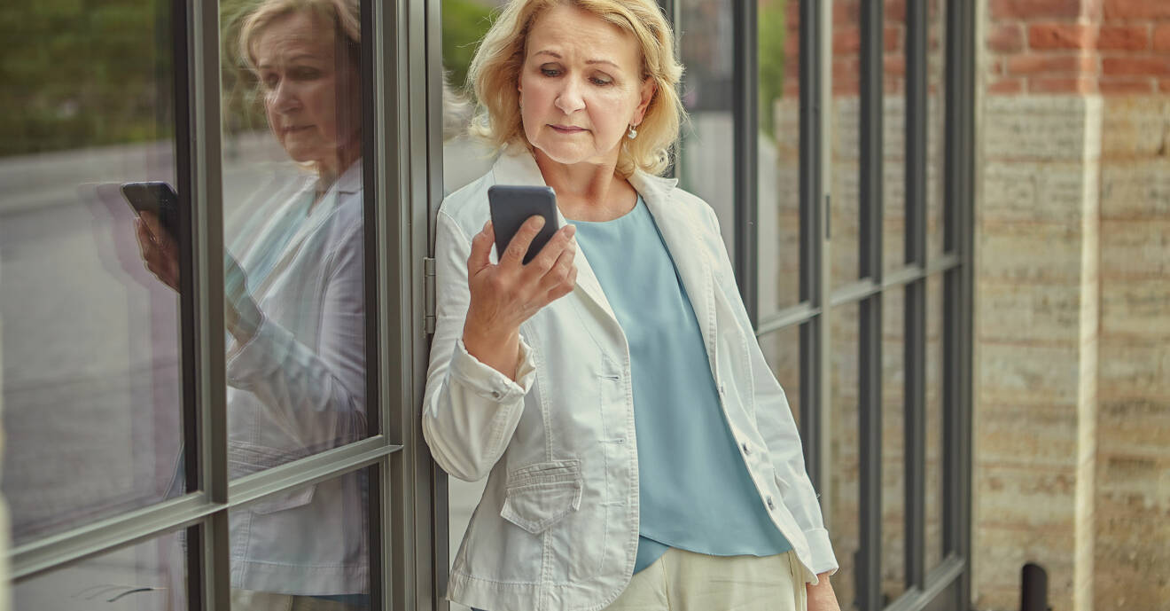 Ensam äldre kvinna med mobiltelefon.