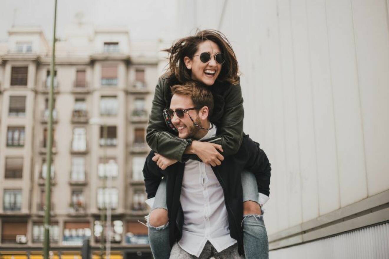 Ett ungt par skrattar tillsammans på en gata.