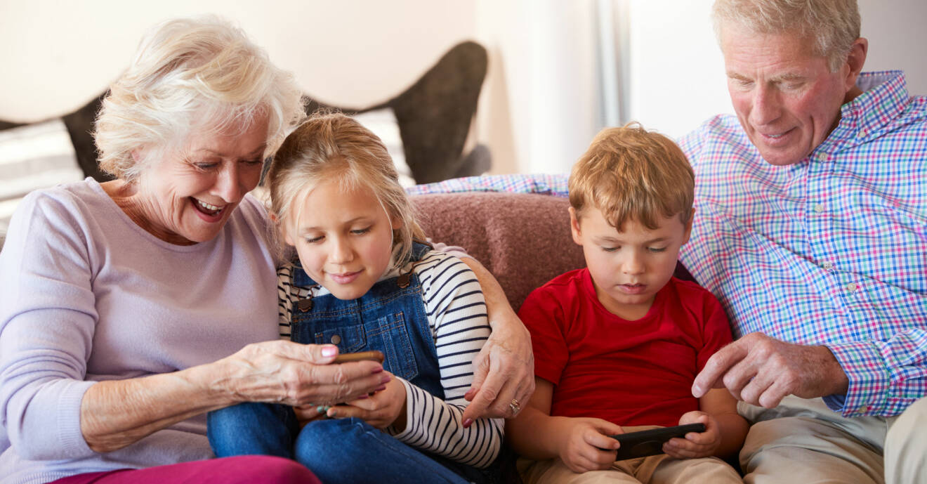 Mormor och morfar spelar spel med barnbarnen på telefonen.