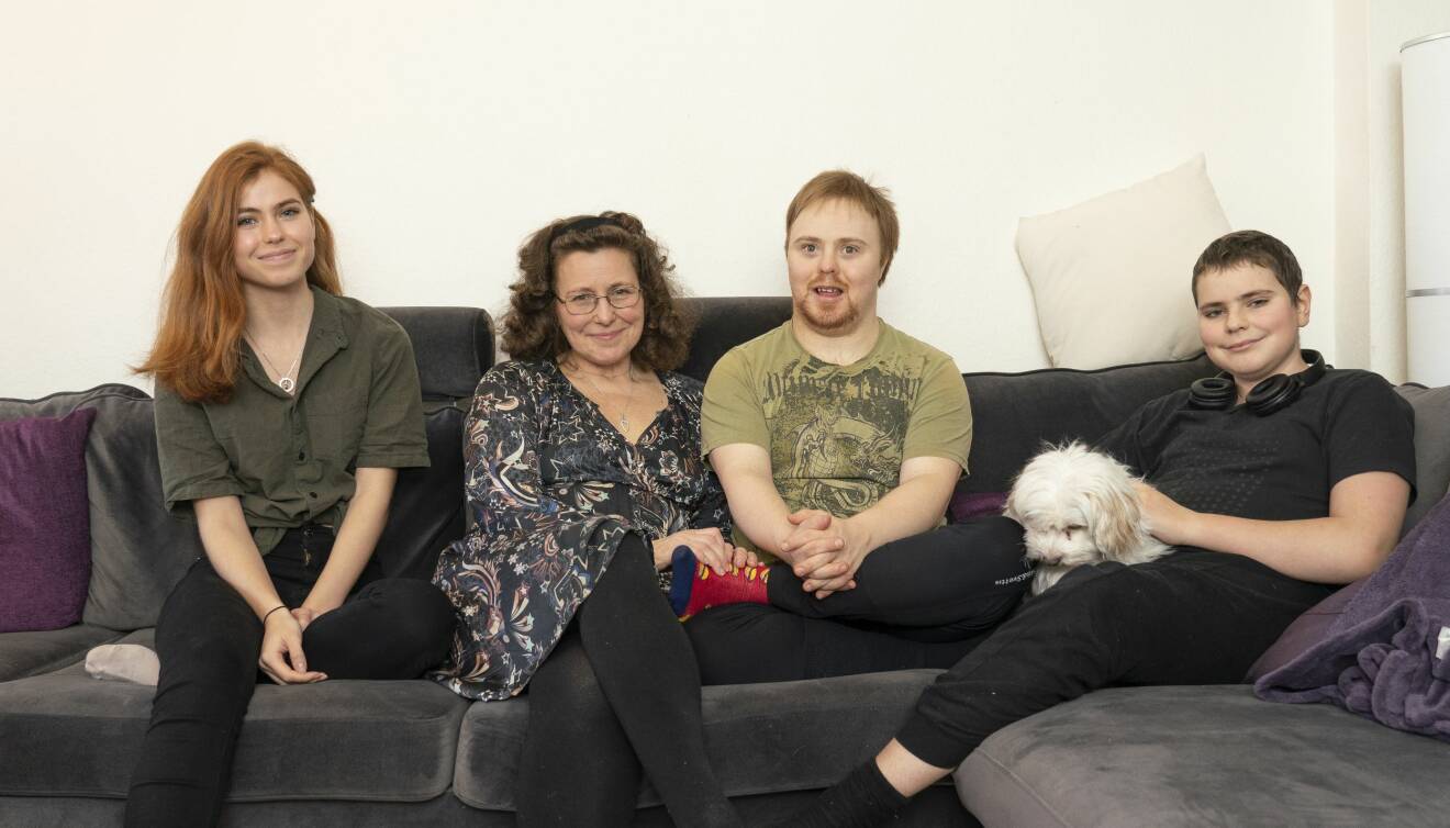 En familj sitter i soffan med en hund.