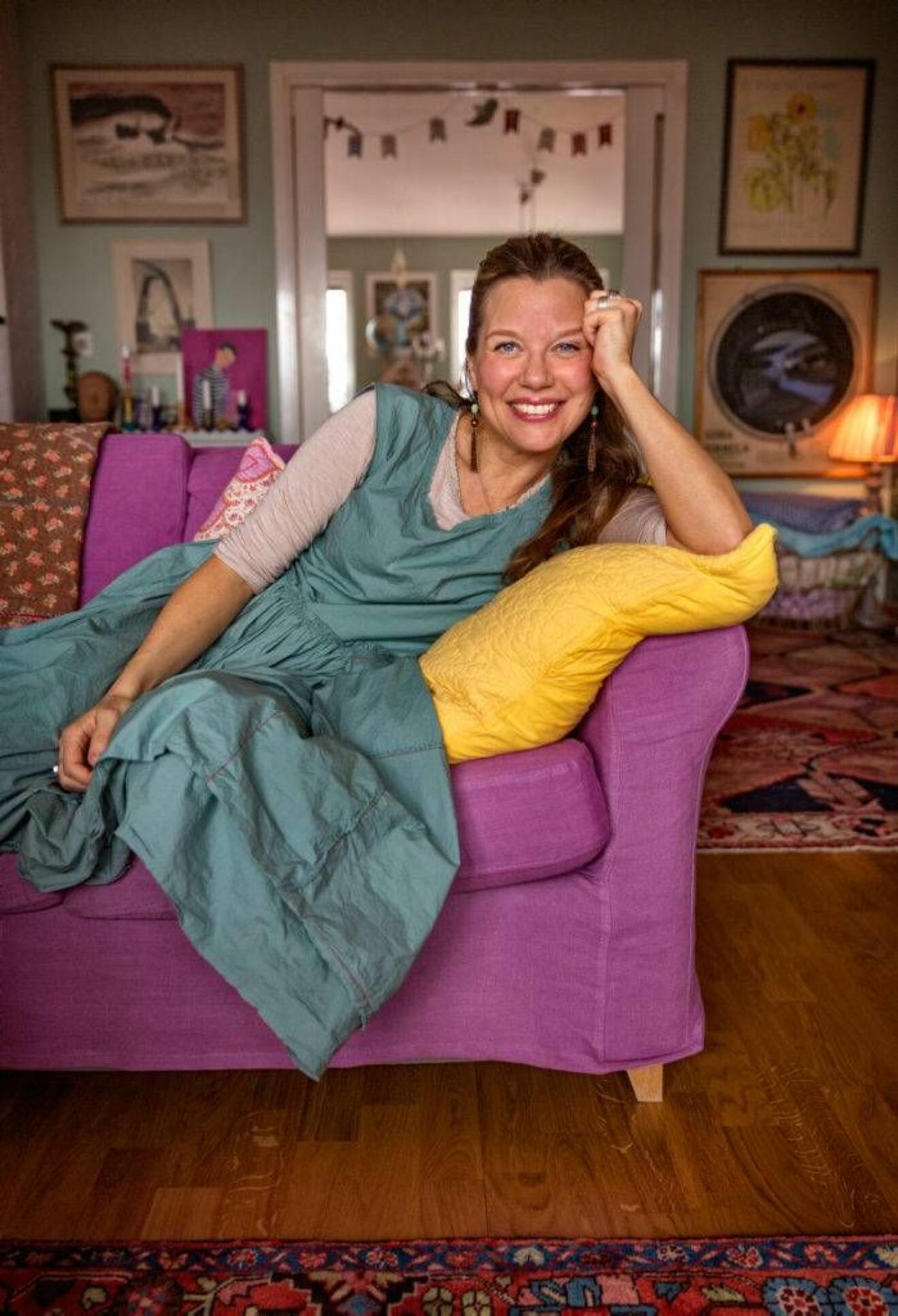 En lila soffa matchas med en gul kudde. Hemma hos Emma är det allt annat än vitt och stilrent. Foto: Ulf Berglund