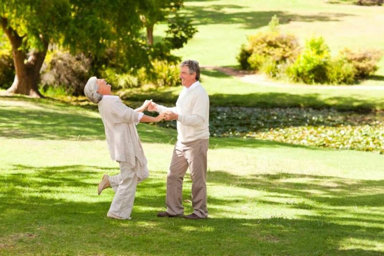 Ett äldre par dansar på en gräsmatta.