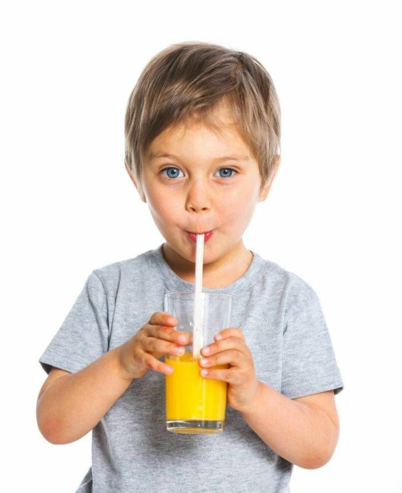 Liten pojke dricker juice med sugrör.