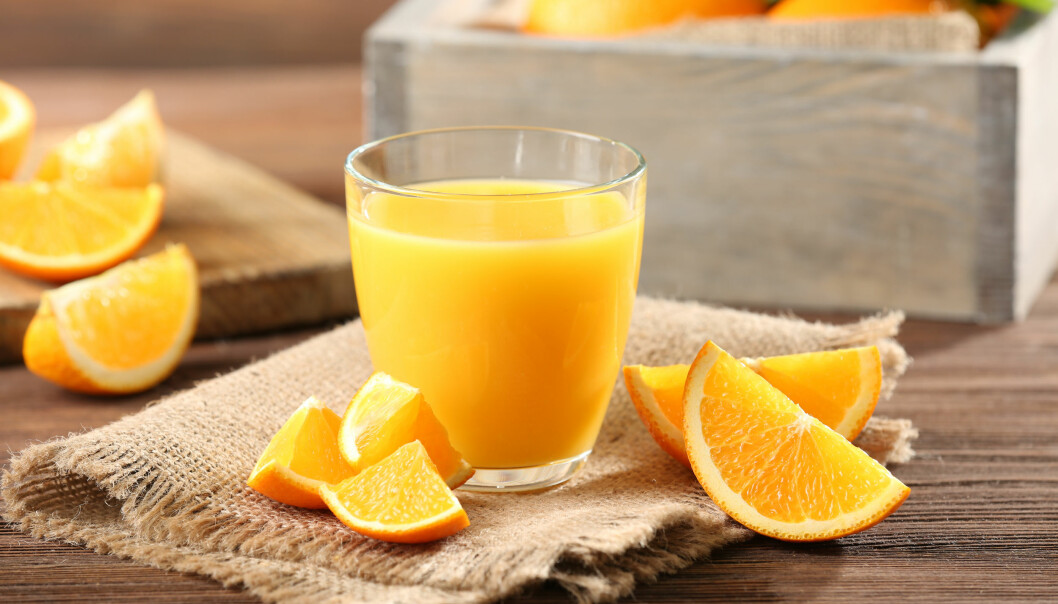Apelsinjuice – även färskpressad – innehåller massor av socker. Ett glas med apelsinjuice och några apelsinklyftor på ett bord.
