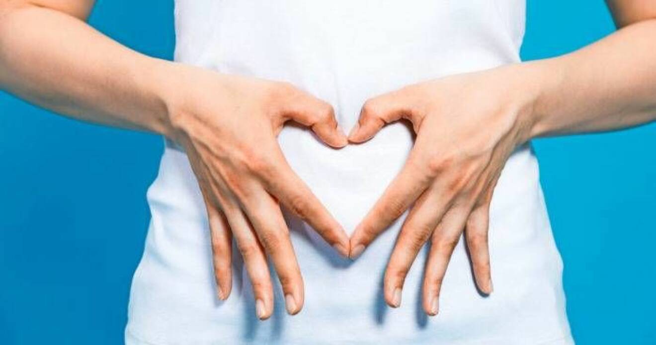 Kvinna som formar sina händer till ett hjärta över magen.