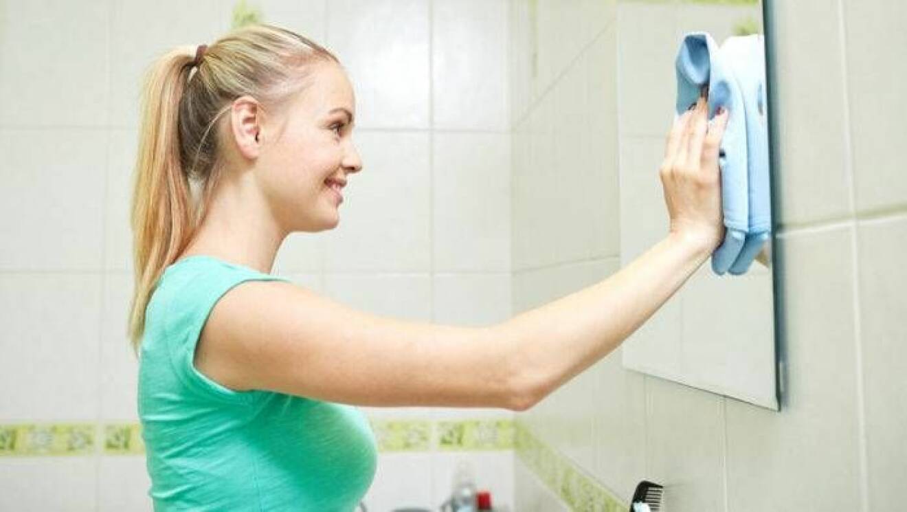 En kvinna putsar sin spegel.