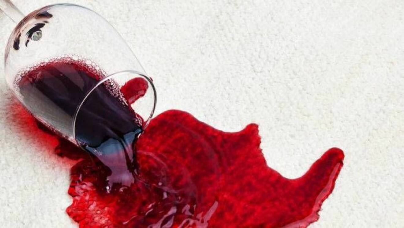 Utspillt rödvin på en vit matta.