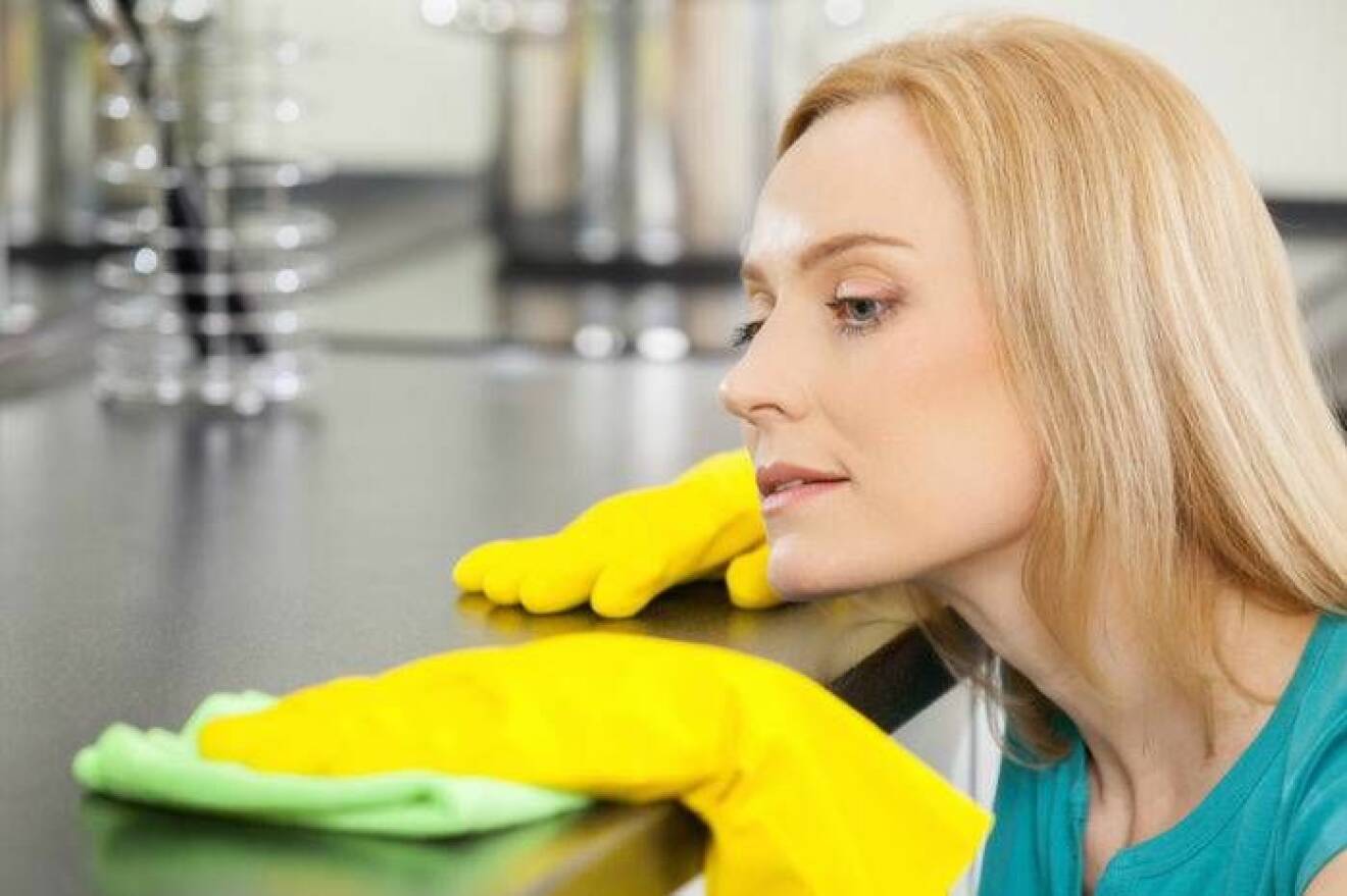 En kvinna rengör diskbänken med en disktrasa.