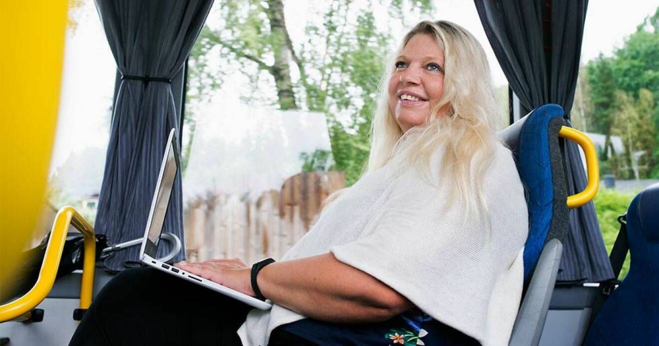 Författaren Anna Ihrén sitter på en buss och ler.