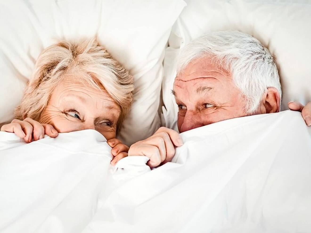 Äldre par som ligger under täcket