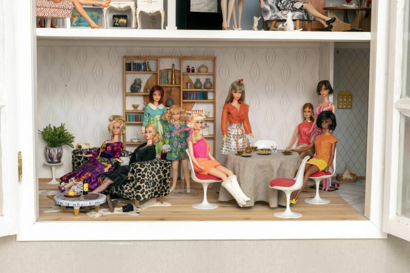 Barbies i vardagsrum i ett dockskåp.