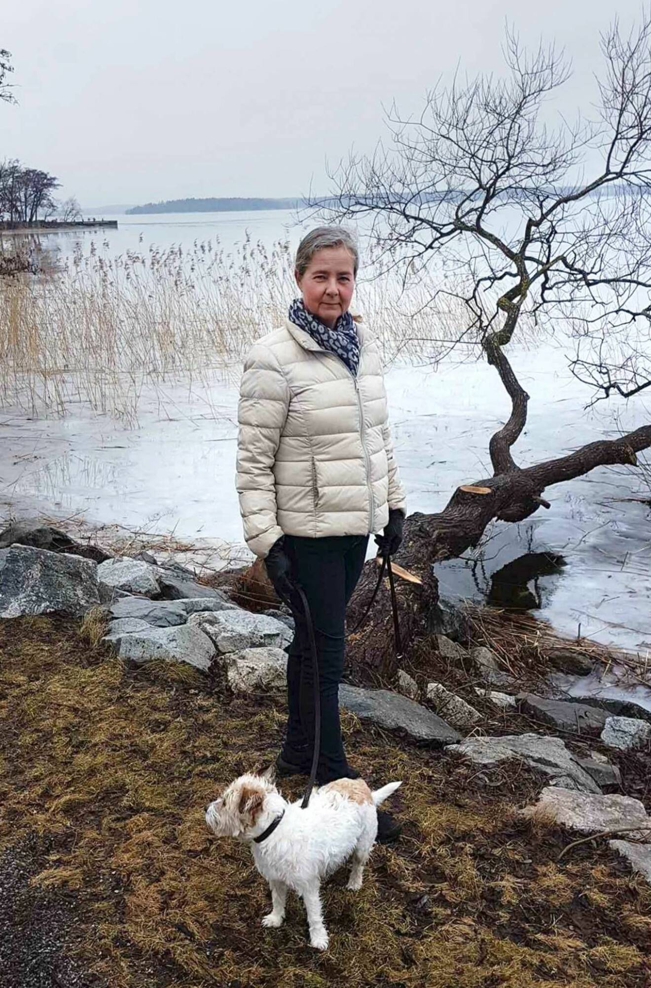 Annalena Svensson står vid vattnet tillsammans med sin hund.