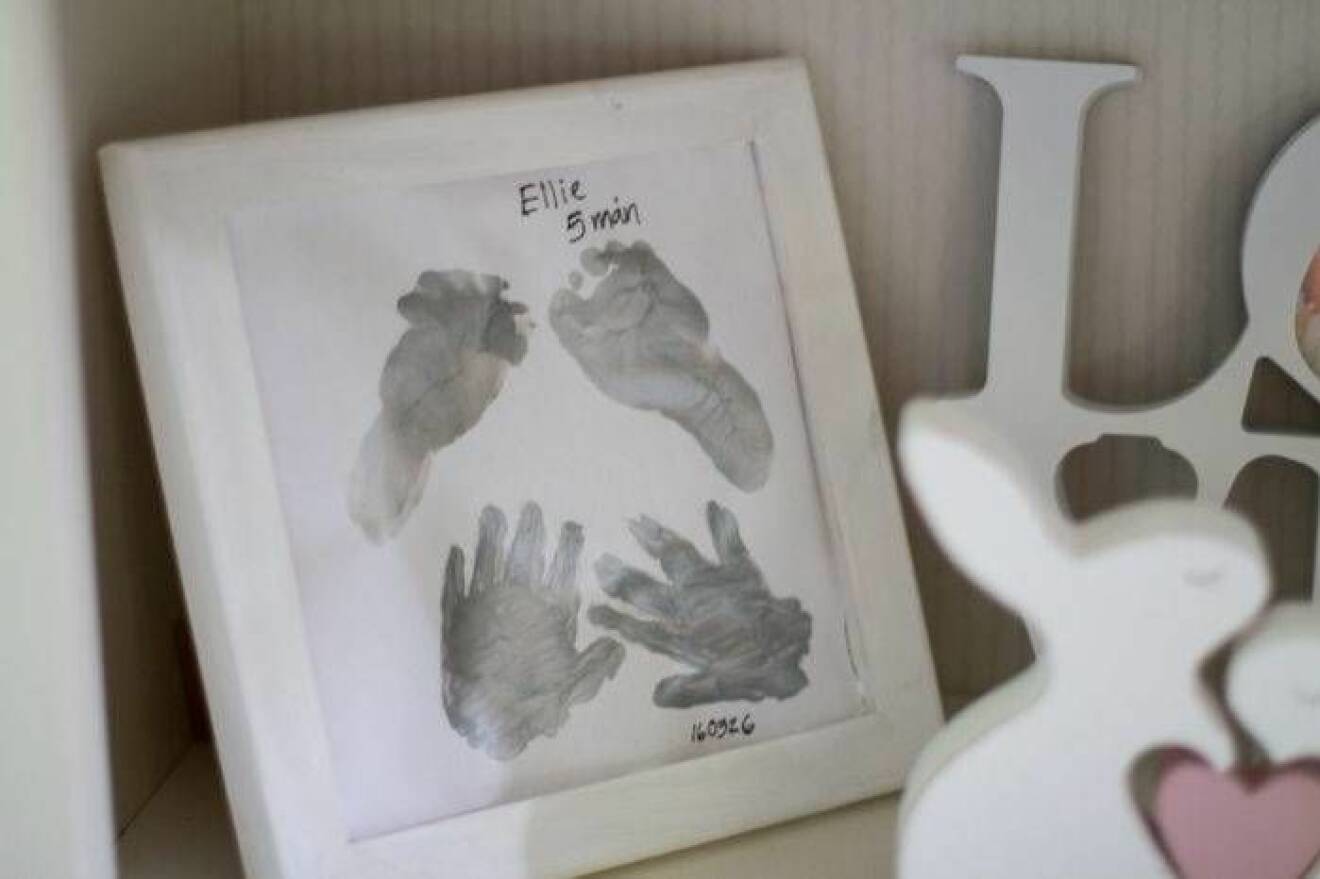 Hand- och fotavtryck från Ellie, fem månader, på hedersplats i bokhyllan.