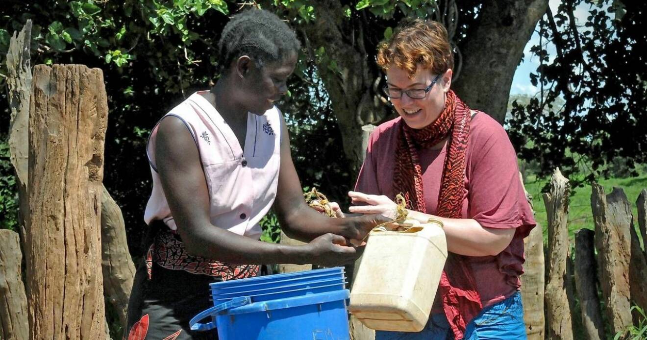 Lisa Johansson hämtar vatten med en zambisk kvinna.