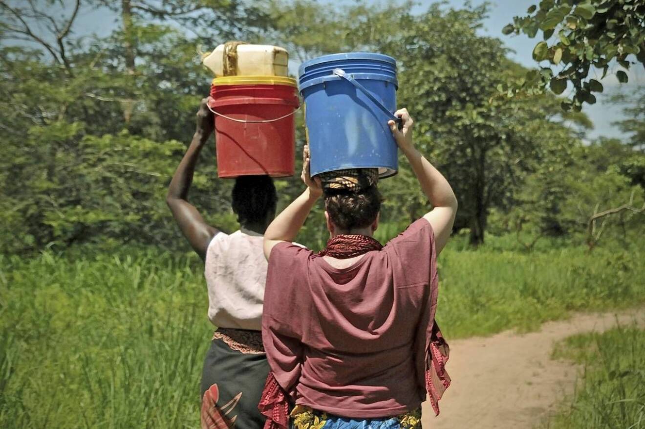 Två kvinnor bär hem vatten på huvudet