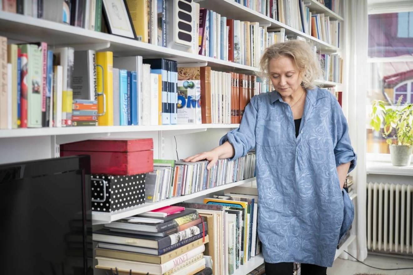 Karin Alvtegen står vid en bokhylla