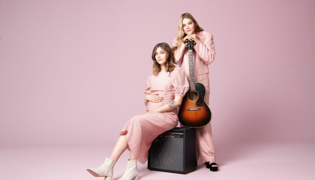 Johanna och Klara Söderberg. Johanna och Klara Söderberg i First aid kit med gitarr och förstärkare mot en rosa bakgrund.