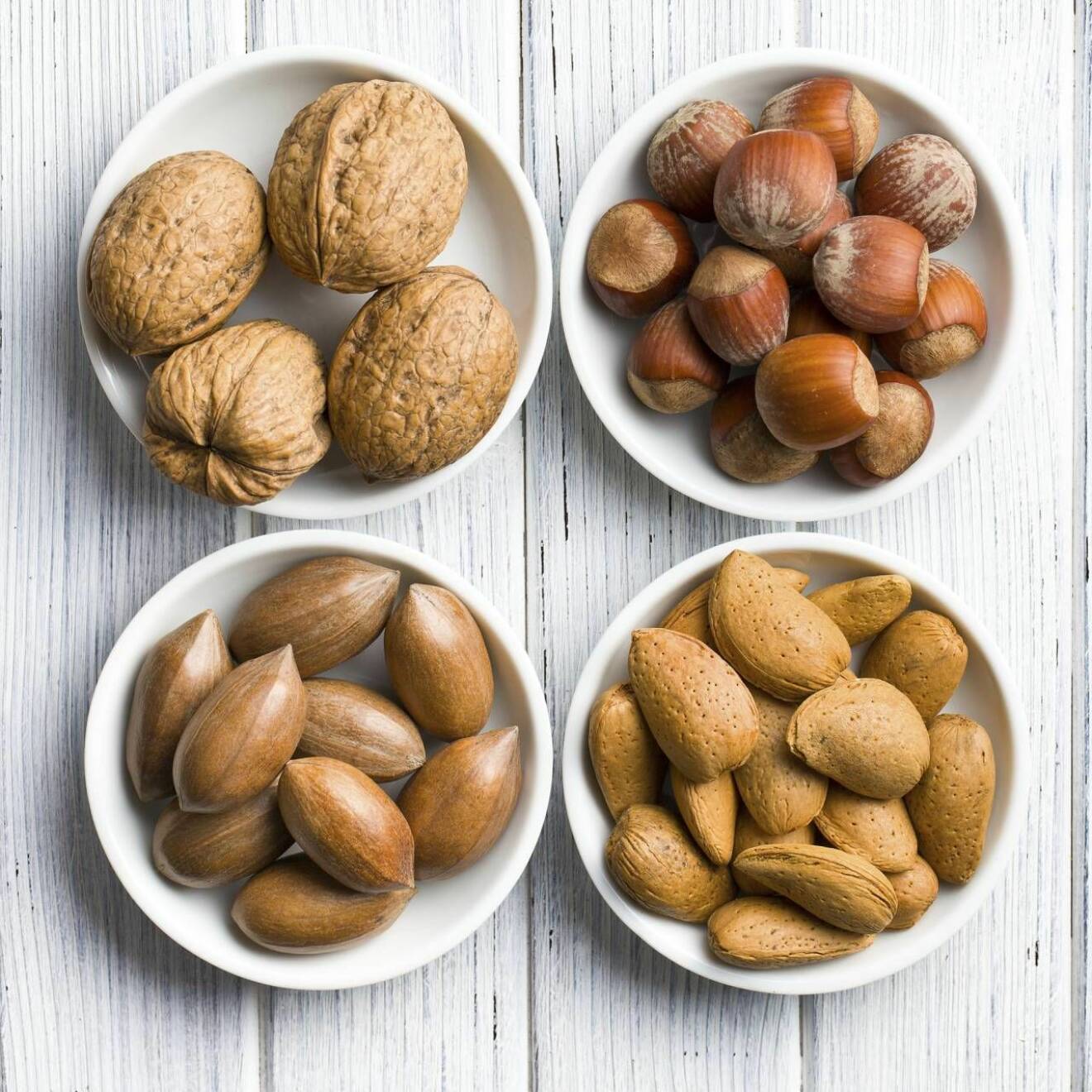 Fyra sorters nötter i olika skålar 