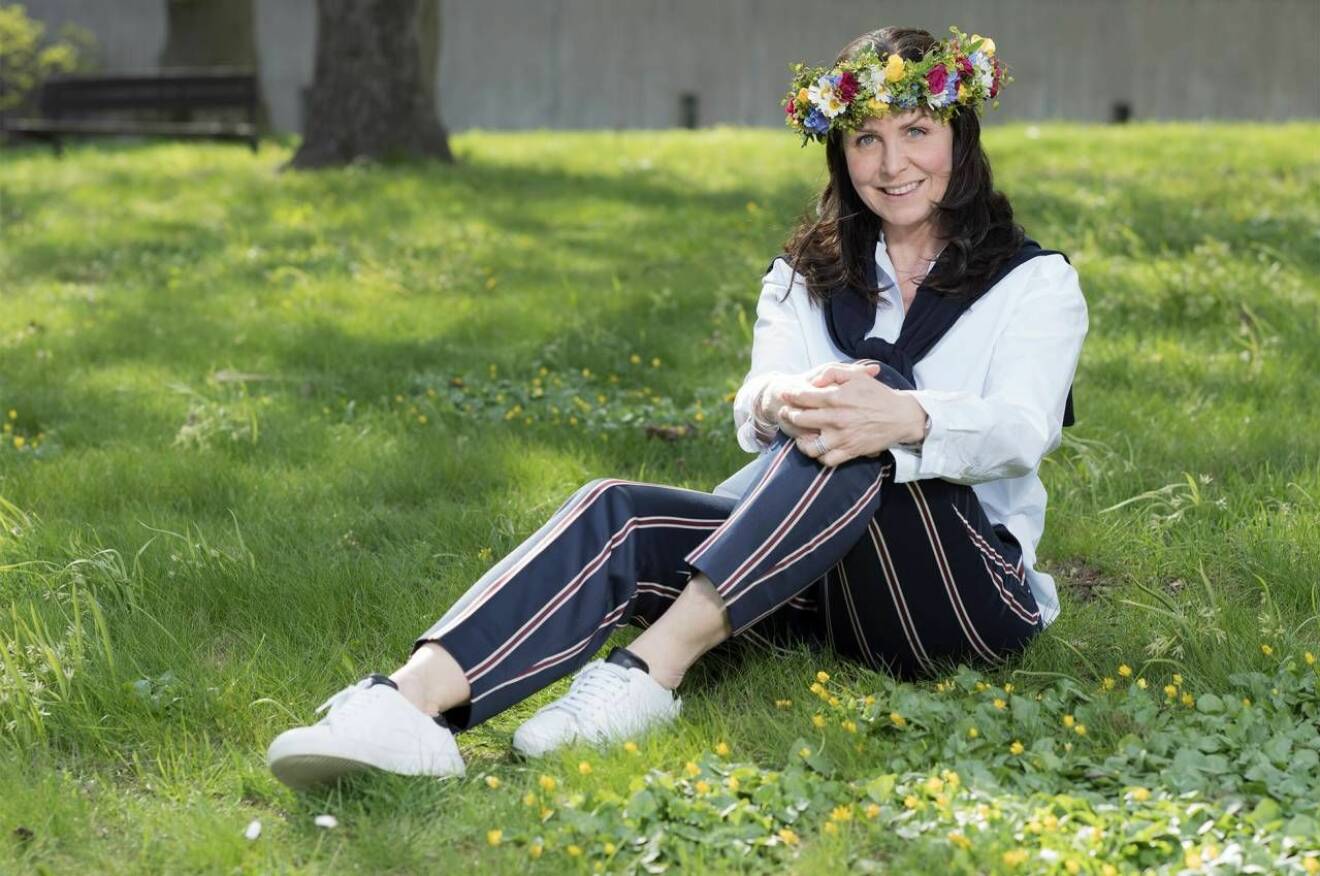 Radioprofilen Titti Schultz sitter i gräset med blomsterkrans i håret.