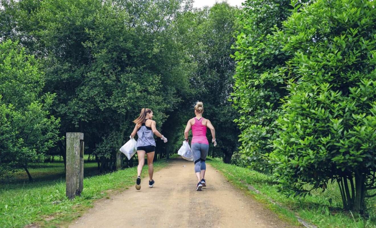 Två kvinnor joggar och plockar skräp