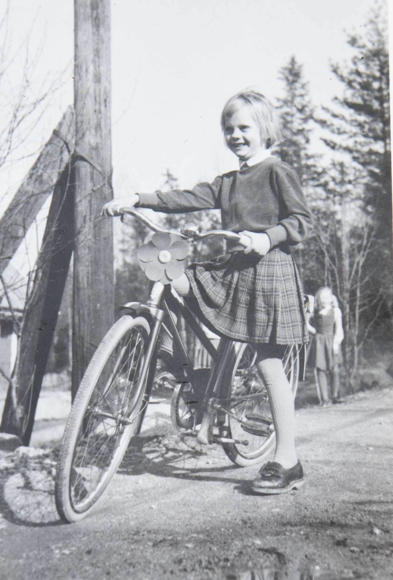Gammalt foto på liten flicka med stor cykel.