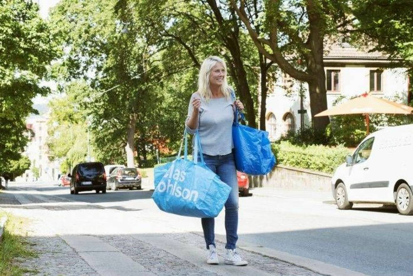 Kvinna på gata med två fullpackade blå plastkassar, en från Ikea och en från Clas Ohlson.
