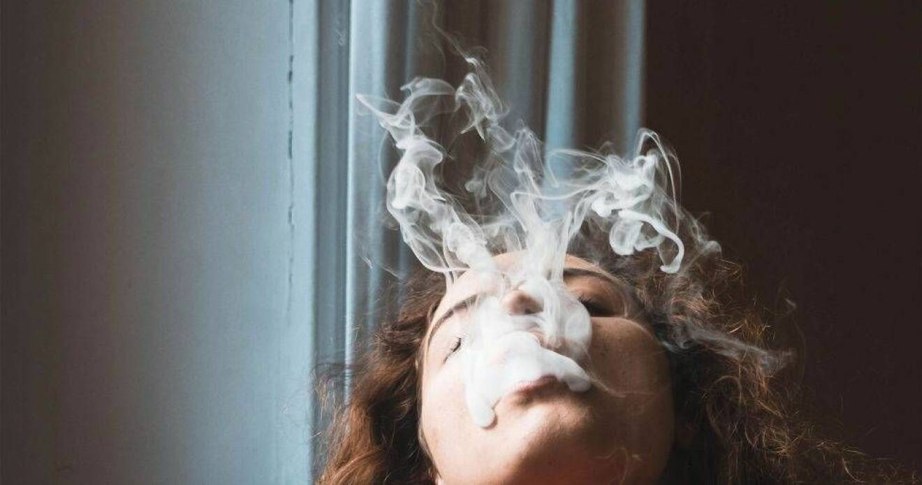 Kvinna som blåser ut rök upp i luften.