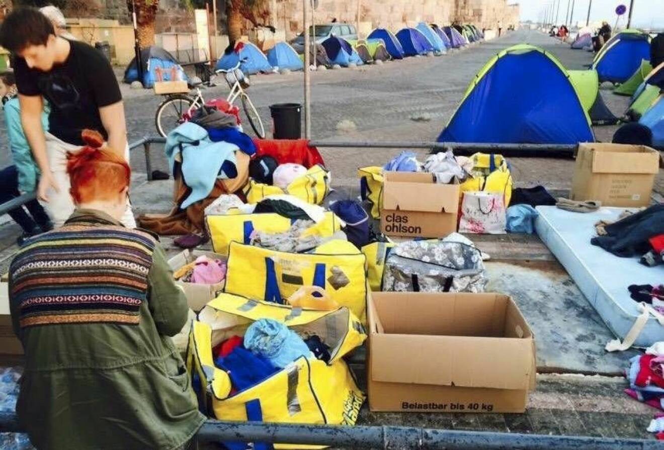 Volontärer delar ut kläder, mat och vatten till behövande. Flyktingar campar i tält på gatan framför.