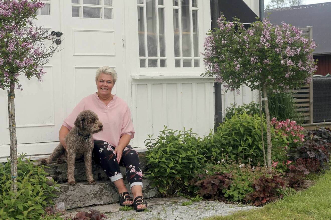 Marie Andersson framför huset tillsammans med en grå hund