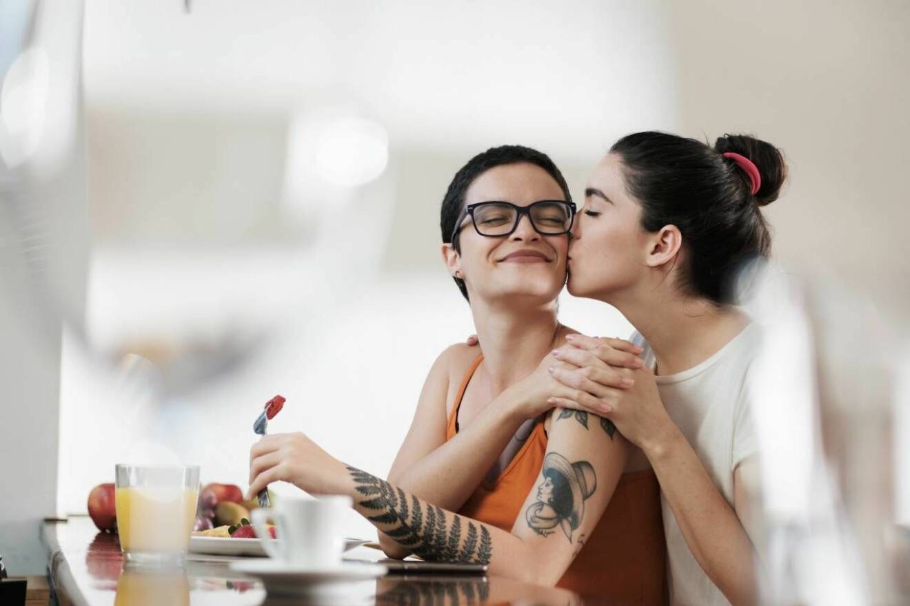 Två kvinnor pussas vid ett bord