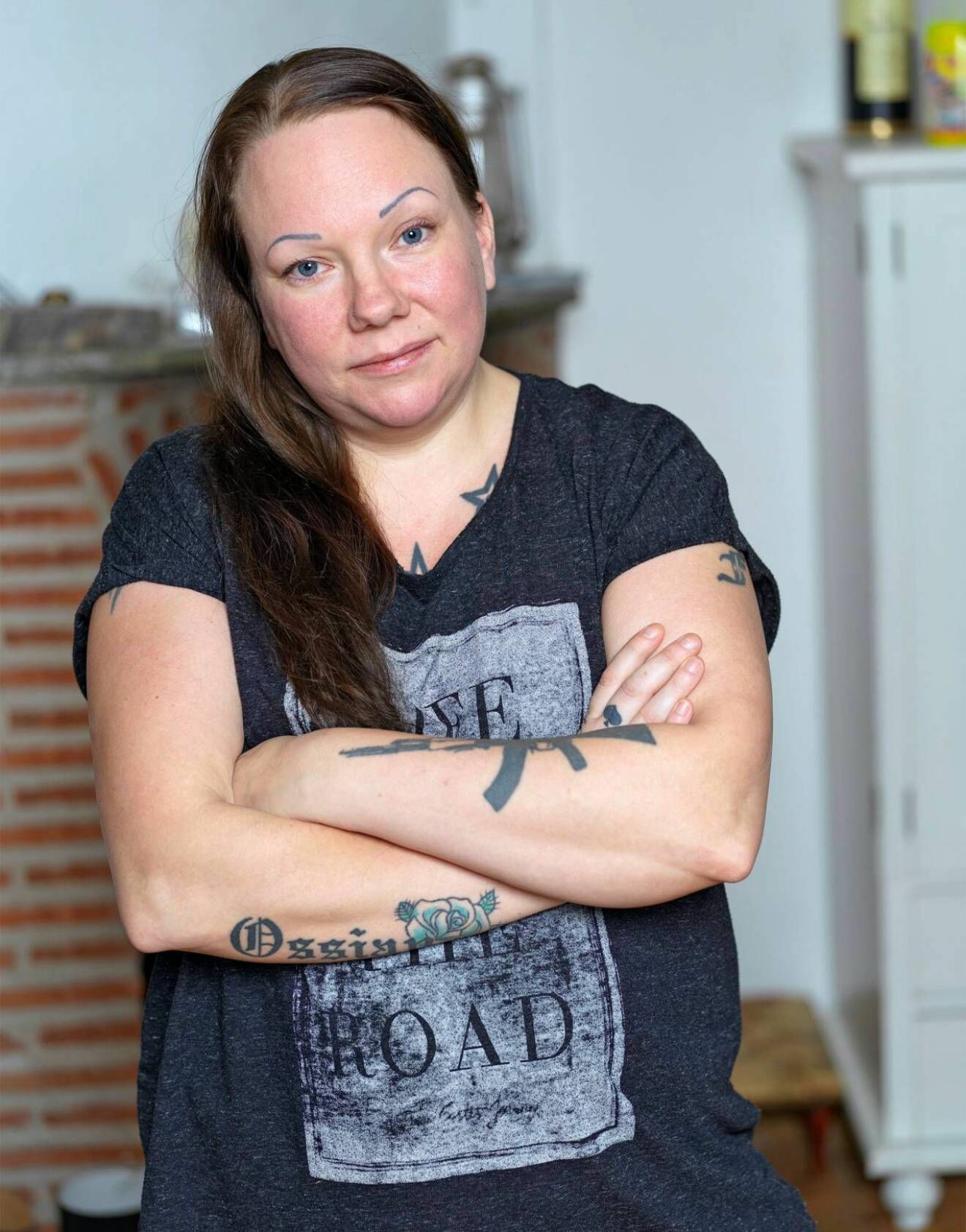 En ung kvinna, Ida, med tatueringar står med armarna i kors.