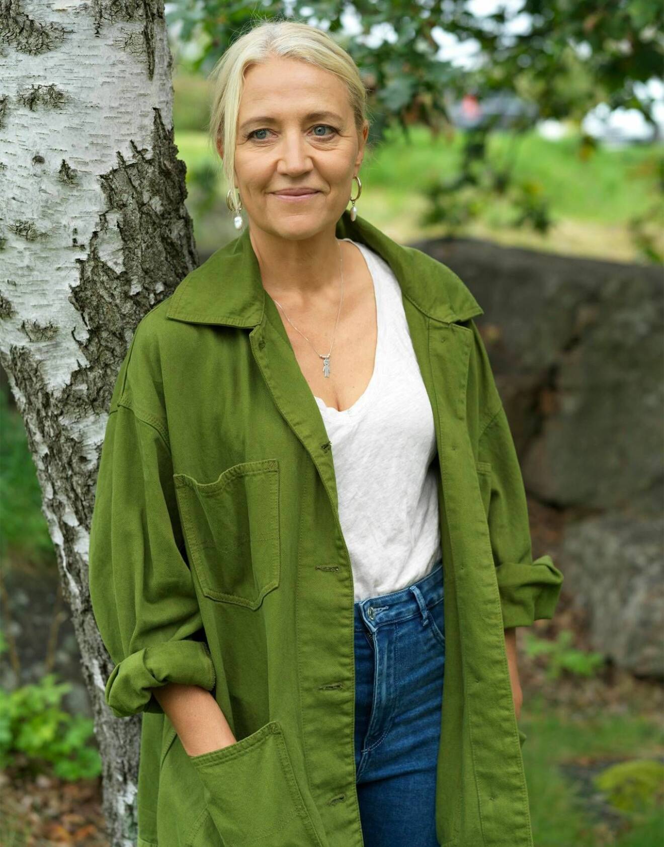 Skådespelaren Klara Zimmergren står i grön skjorta vid en björk.