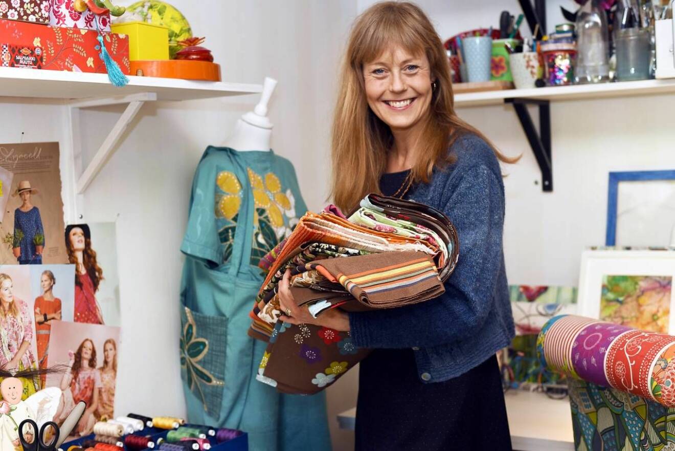 Ann-Sofie, som brinner för hållbart mode, står i sin ateljé med tyger i handen. 
