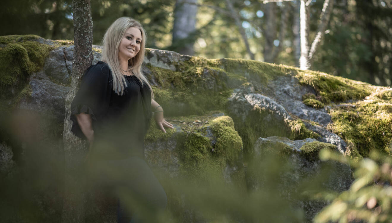 Heidi Mattsson som drabbades av hjärtinfarkt står och poserar i skogen.