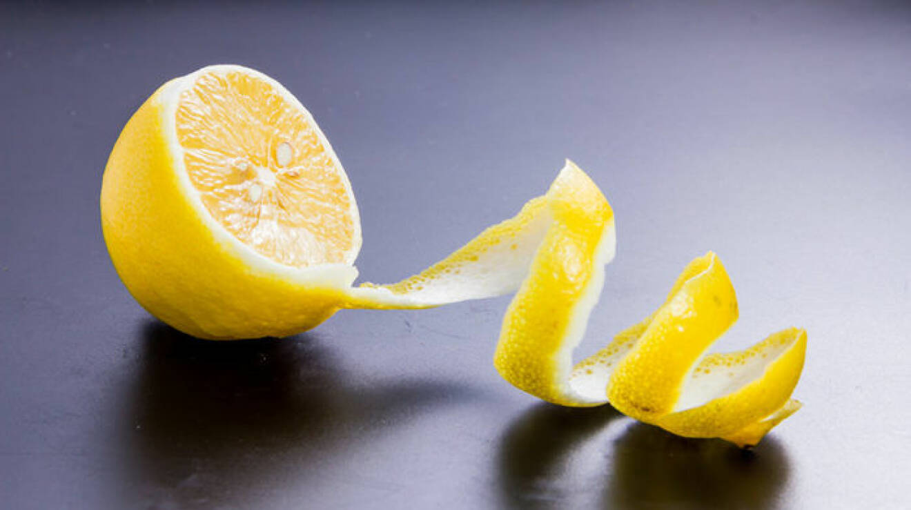 Bild på en citronhalva med en bit av skalet i spiral.